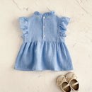 Blue dress with ruffled sleeves on a textured beige surface