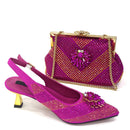 A pair of bright magenta slingback high-heel pumps with gold and rhinestone embellishments, shown alongside a matching rhinestone clutch handbag with gold chain straps on a white background, Obroi