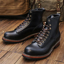 Pair of black leather boots with brown laces on a wooden floor, Obroi