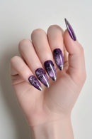Hand with purple and silver nail art on a neutral background, Obroi