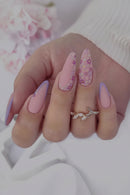 Close-up of a hand with pink and purple nail polish and a decorative ring, Obroi