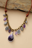 Necklace with purple and gray beads and a large purple stone pendant on a beige background, Obroi