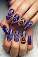 Nails with floral designs in blue, purple, and gold on a neutral background, Obroi