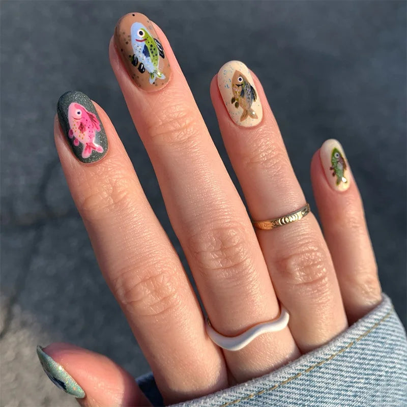 Nails with fish design held against a dark background,Obroi