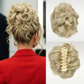 A blonde curly hairpiece shown worn on a woman's head from the back, alongside two close-up views of the hairpiece itself on a light background. The hairpiece is secured with a cream-colored claw clip, Obroi