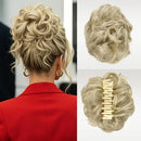 A blonde curly hairpiece shown worn on a woman's head from the back, alongside two close-up views of the hairpiece itself on a light background. The hairpiece is secured with a cream-colored claw clip, Obroi