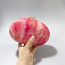 Pink and gold marbled clutch held by a hand on a white background, Obroi