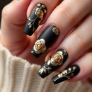Black nails with gold floral designs on a neutral background, Obroi