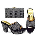 Black high-heeled shoes with white rhinestone details and a matching clutch on a white background, Obroi