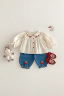 Children's outfit with blouse, shorts, shoes, and a toy on a light background, Obroi