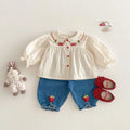 Children's outfit with blouse, shorts, shoes, and a toy on a light background, Obroi