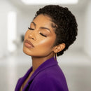 Woman with short curly hair wearing a purple top against a neutral background, Obroi