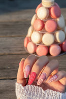 A close-up of a hand showcasing a set of long, almond-shaped press-on nails with a pink and white strawberry theme. The nails feature a 3D strawberry texture on one finger, a striped pattern on another, and delicate pearl details on a white lace sleeve, Obroi