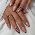 Obroi Close-up of a hand with pink and leopard print nail design on a white background