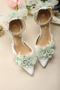 White high-heeled shoes with floral decorations on a beige background, Obroi