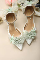 White high-heeled shoes with floral decorations on a beige background, Obroi