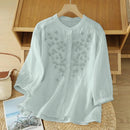Light green blouse on a wooden hanger against a wooden shelf background, Obroi