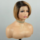 A short bob wig with dark brown roots and warm blonde highlights, styled on a mannequin bust against a light gray background, Obroi