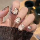 Obroi Close-up of a hand with stylish nail design featuring beige, white, and silver colors.