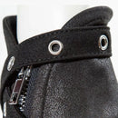 Close-up of a black textured fabric boot or shoe detail with a zipper and metal grommets on a white mannequin, Obroi