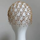 Beaded headpiece on a mannequin head against a gray background, Obroi