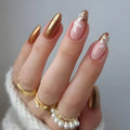 Hand with gold and pink nail design wearing gold rings on a neutral background, Obroi