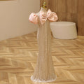 Mannequin wearing a sparkly dress with pink bows on a wooden floor, Obroi