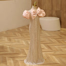 Mannequin wearing a sparkly dress with pink bows on a wooden floor, Obroi