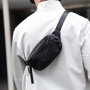 Person wearing a black crossbody bag on a blurred background, Obroi