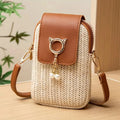 Small woven handbag with brown leather accents and a cat-shaped keychain on a wooden surface, Obroi