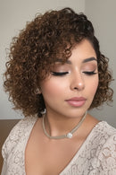 Woman with styled hair and makeup against a neutral background, Obroi