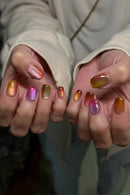 Close-up of hands with multicolored nail polish against a neutral background, Obroi