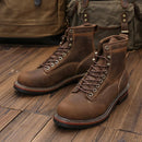 Pair of brown leather boots on a wooden floor with a bag in the background, Obroi
