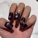 Hand with dark purple nail polish and decorative elements on a white background, Obroi