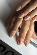 Close-up of a hand with floral nail art on a white surface, Obroi