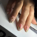 Close-up of a hand with decorative nail art on a white surface, Obroi
