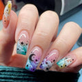 Nails with colorful designs featuring stars and moons on a blurred background, Obroi