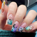 Nails with colorful designs featuring stars and moons on a blurred background, Obroi