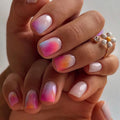 Close-up of a hand with gradient nail art on a neutral background, Obroi