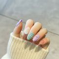 Close-up of a hand with pastel nail art on a blurred background, Obroi