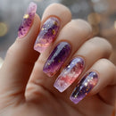 Hand with purple and pink galaxy-themed nail art on a blurred background