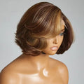 A short layered wig displayed on a mannequin head against a plain light gray background. The wig has medium brown roots with warm caramel and honey blonde highlights throughout, styled in a bob cut with soft waves, Obroi