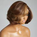 A short layered wig displayed on a mannequin head against a plain light gray background. The wig has medium brown roots with warm caramel and honey blonde highlights throughout, styled in a bob cut with soft waves, Obroi