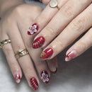 Close-up of hands with red nail polish and floral designs on a neutral background, Obroi