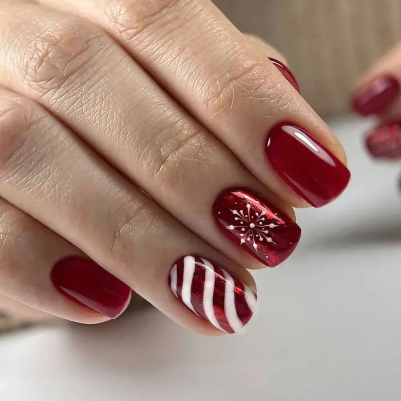 Close-up of a hand with red nail polish featuring a snowflake design on a neutral background, Obroi