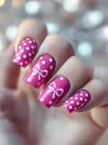 Nails with pink polish and white polka dots, featuring a central bow design, Obroi