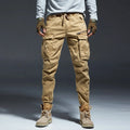 Person wearing tan cargo pants and brown boots on a gray background, Obroi