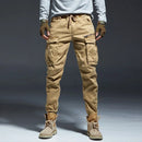 Person wearing tan cargo pants and brown boots on a gray background, Obroi