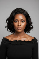 Woman with styled hair wearing a black off-shoulder top against a gray background, Obroi