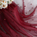 Red fabric with bead embellishments and a bouquet of flowers on a white background, Obroi